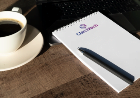 Mesa de madera con bloque de notas y bolígrafo con imagen corporativa de Clerchtech